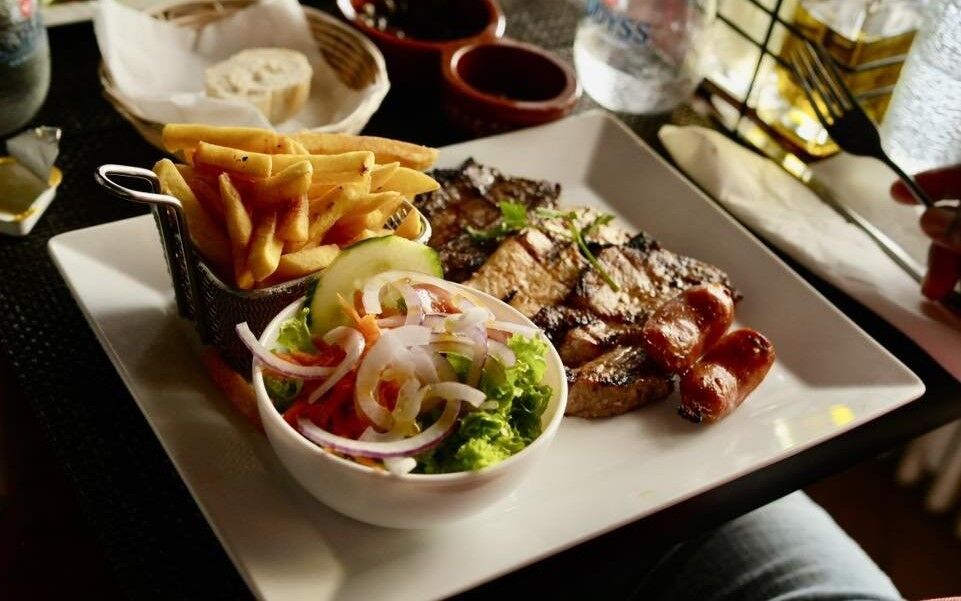 Prato gastron&ocirc;mico com carne, batatas fritas e salada em um restaurante luxemburgu&ecirc;s