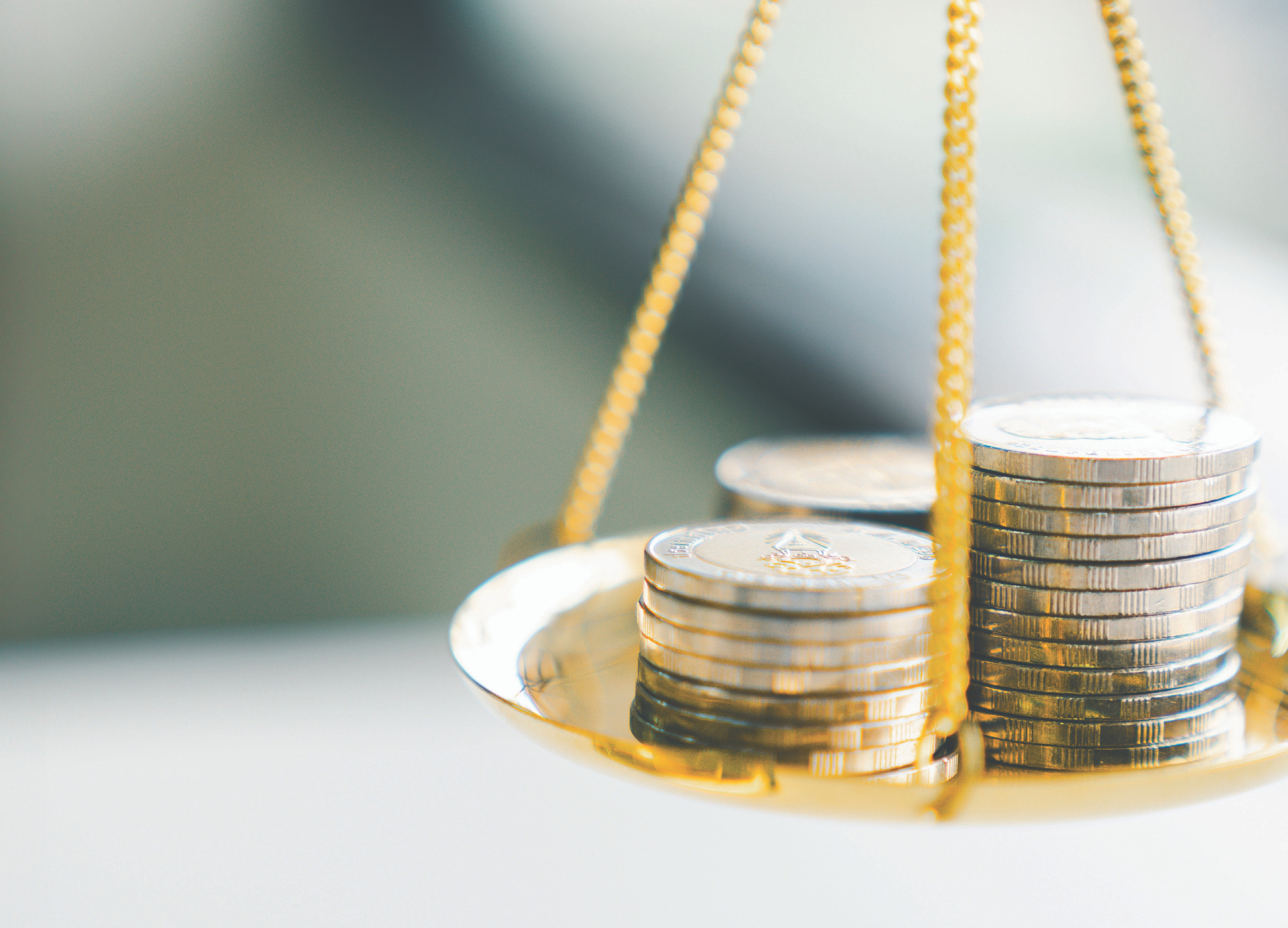 Close-up of a golden balance scale with stacked coins on one side, symbolizing financial balance