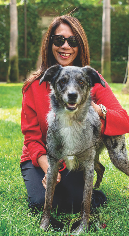 Rianna Riego kneeling on grass with a dog, outdoor portrait