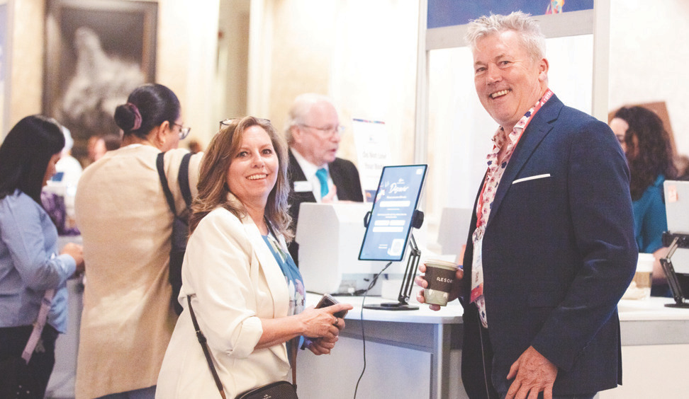Conference attendees at a registration or expo desk interacting with staff.