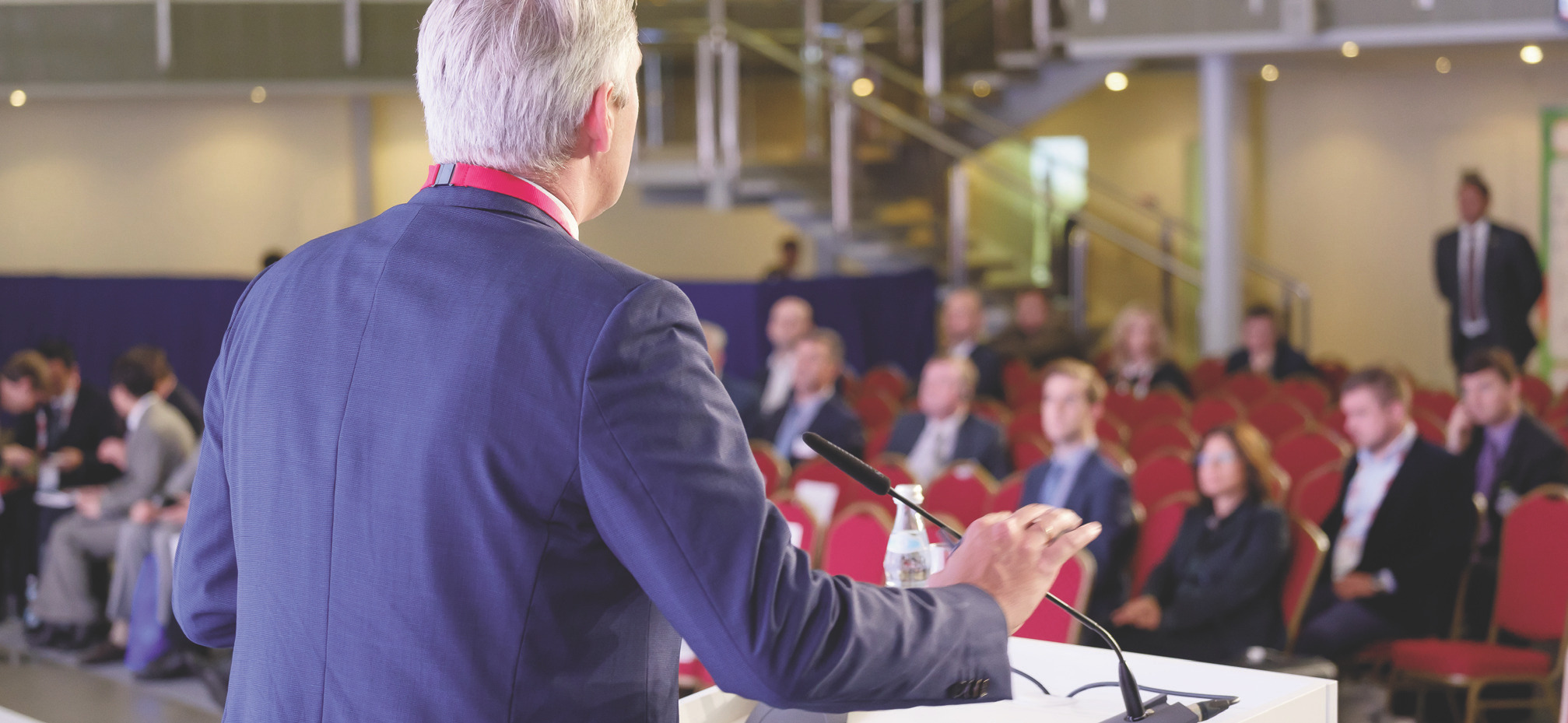 A speaker at a podium addressing an audience during a professional conference
