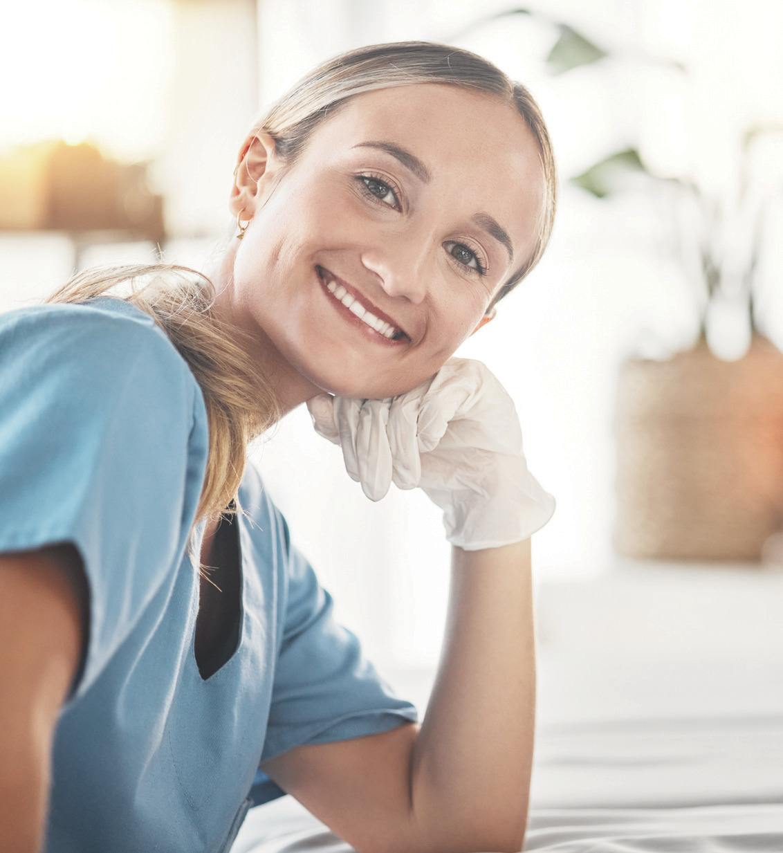 Smiling spa therapist in a light blue uniform.
