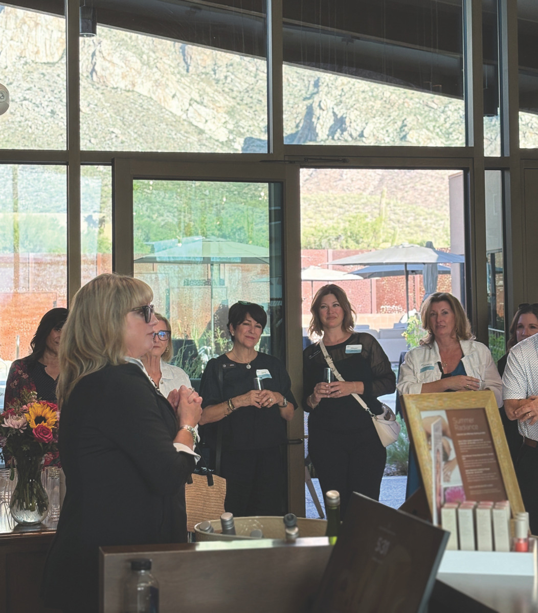 Audience at the reception standing by large windows while a speaker addresses the group
