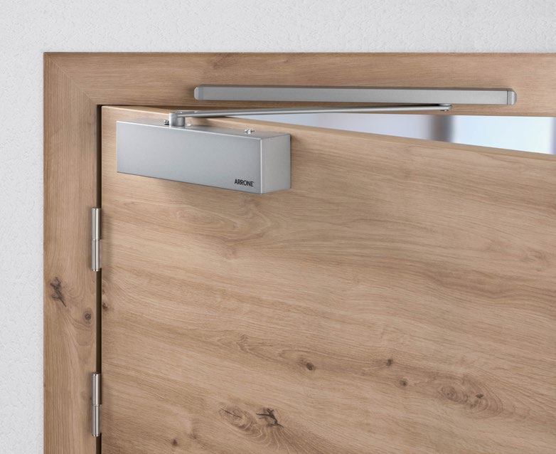 Overhead door closer unit mounted at the top corner of a wooden door