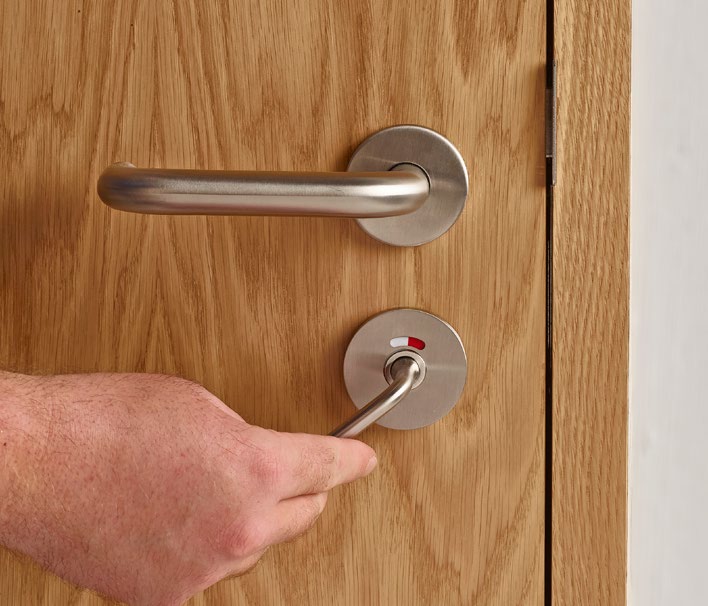 Close-up of a stainless steel lever handle with a hand operating the non-coin release below