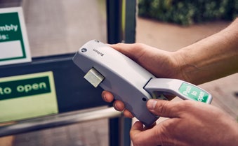 Close-up of hands operating a surface-mounted exit device / panic bar.
