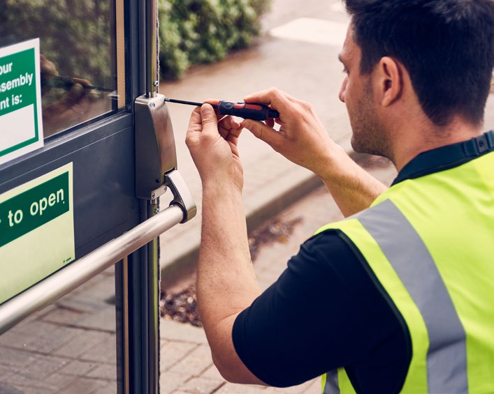Technician adjusting a fire door handle to ensure precise alignment