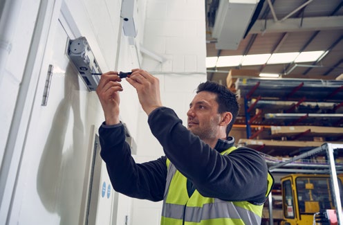 Technician adjusting a door closer mechanism for optimal closing speed