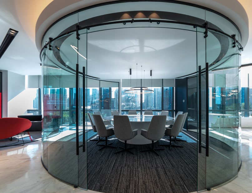 Circular glass meeting room with a round conference table.