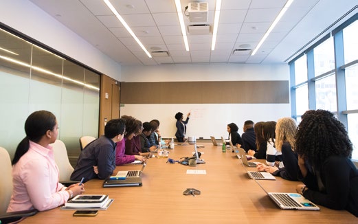 Meeting room with presenter and attendees at a long table.