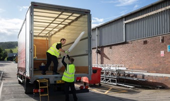 SWS UK staff unloading a delivery from the back of a truck using bespoke racking to secure products.