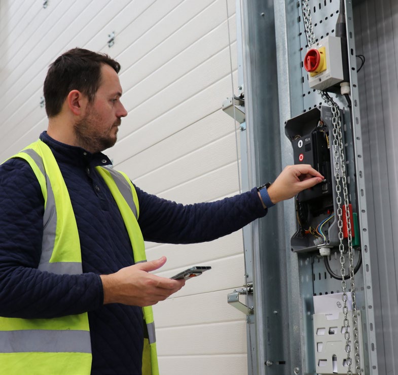 Technician inspecting an industrial door control panel in a plant