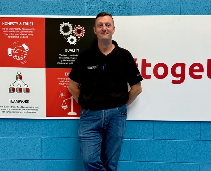 John Lawson standing in front of a Marantec poster and blue wall