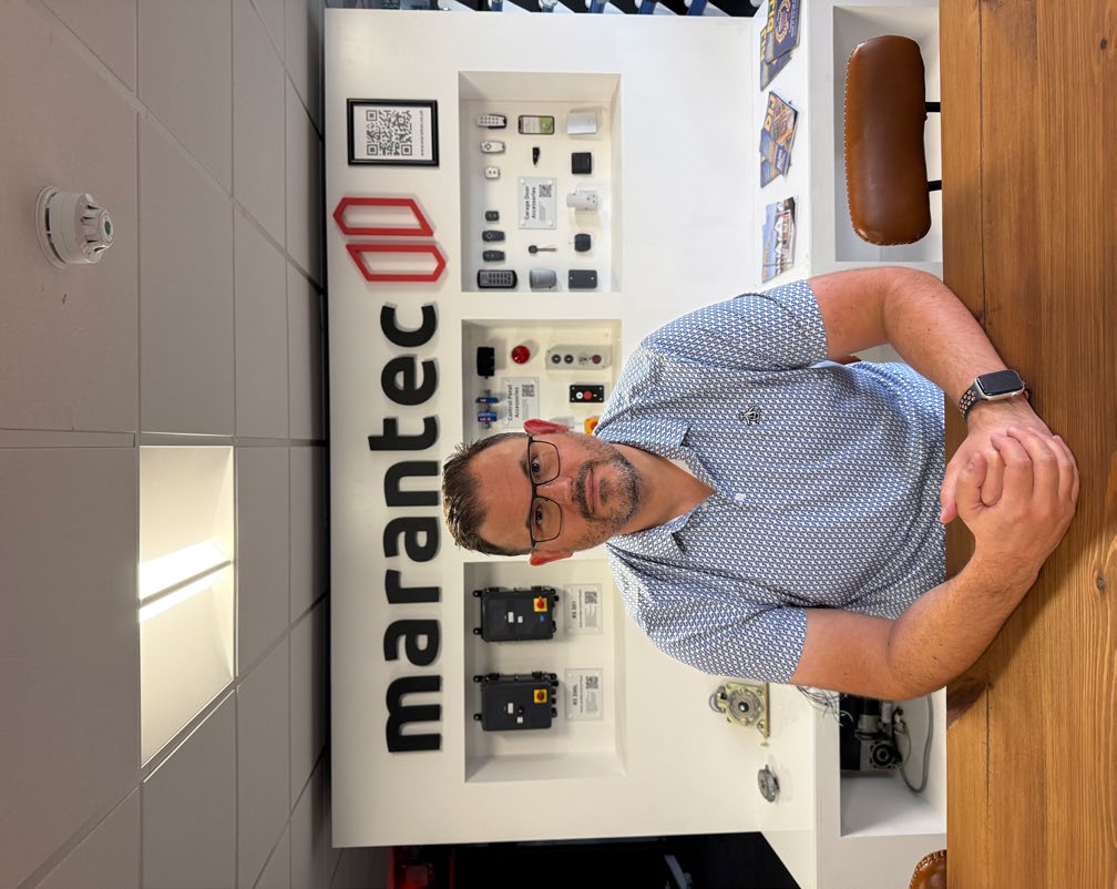 James Matchett seated at a wooden desk with Marantec display behind him