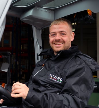 Ryan seated in a vehicle wearing an Ellard-branded jacket, smiling