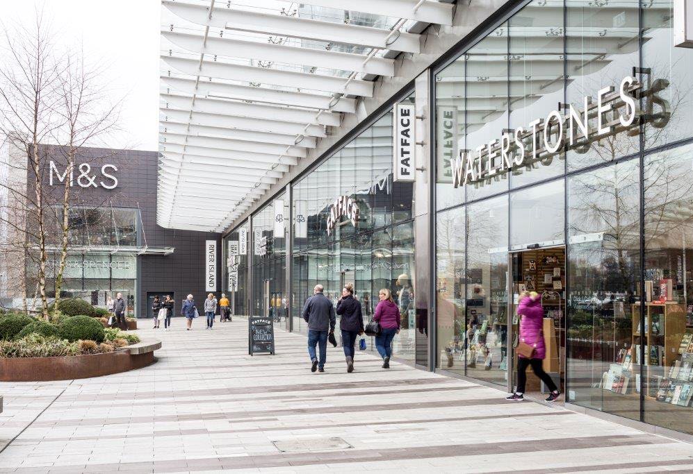 Exterior photograph of Glasgow Fort shopping centre entrance with people passing by and shopfronts.