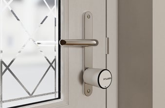 Close-up of Polaris smart door cylinder and turner mounted on the inside of a door beside a handle