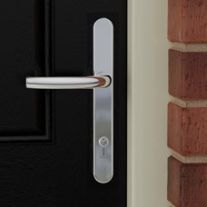 Close-up of a single polished chrome longplate lever handle on a dark door.