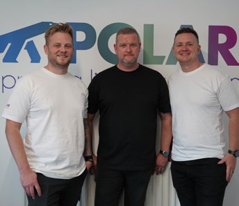 Three Polar NE staff standing together at a Polar NE branded backdrop
