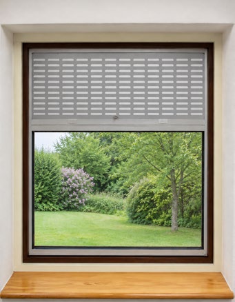 Window with TaktaVent ventilation grille above the upper pane and garden view through the lower pane; wooden sill visible.