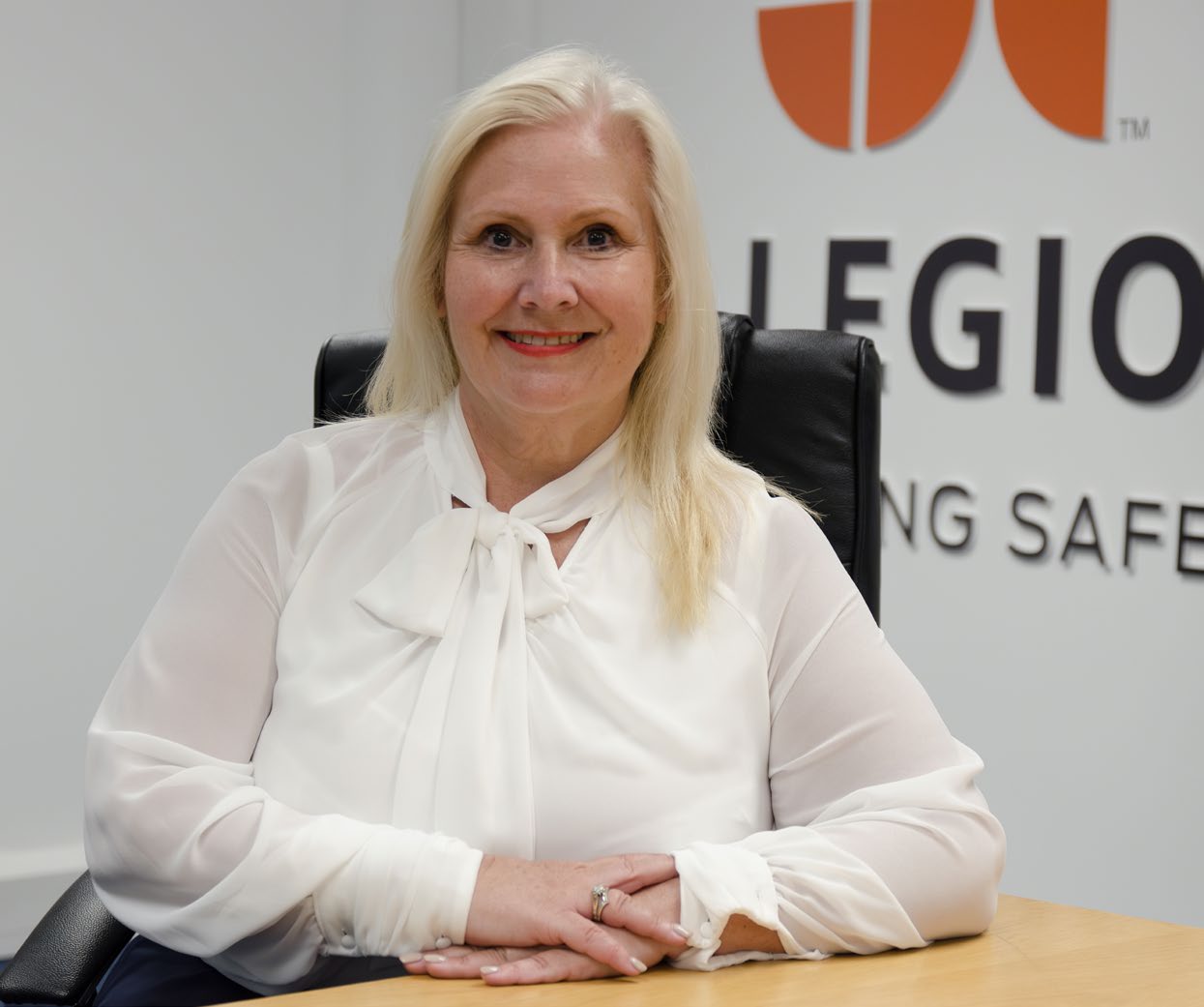 Portrait of Nicola John, Managing Director of Fire Door Maintenance (FDM) Training and Development, seated at a desk and smiling.