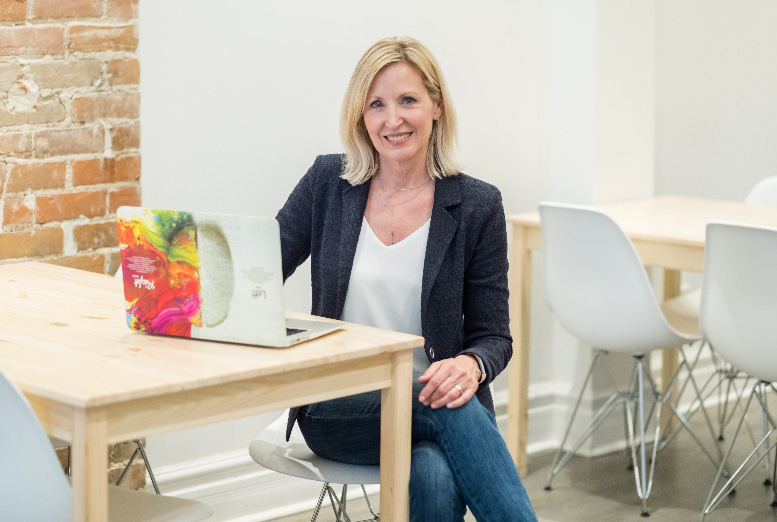 Ann Papayoti seated at a desk with a colorful laptop