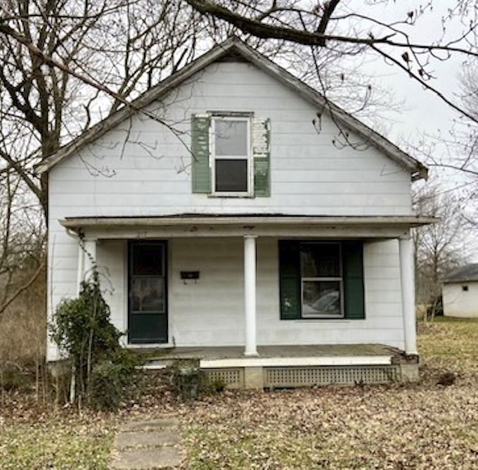 The abandoned white two-story childhood house with a wide front porch