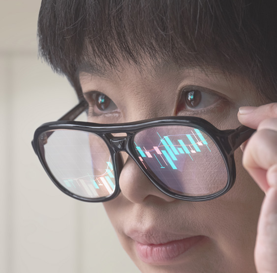 Close-up of a person wearing glasses with turquoise and red data charts reflected in the lenses