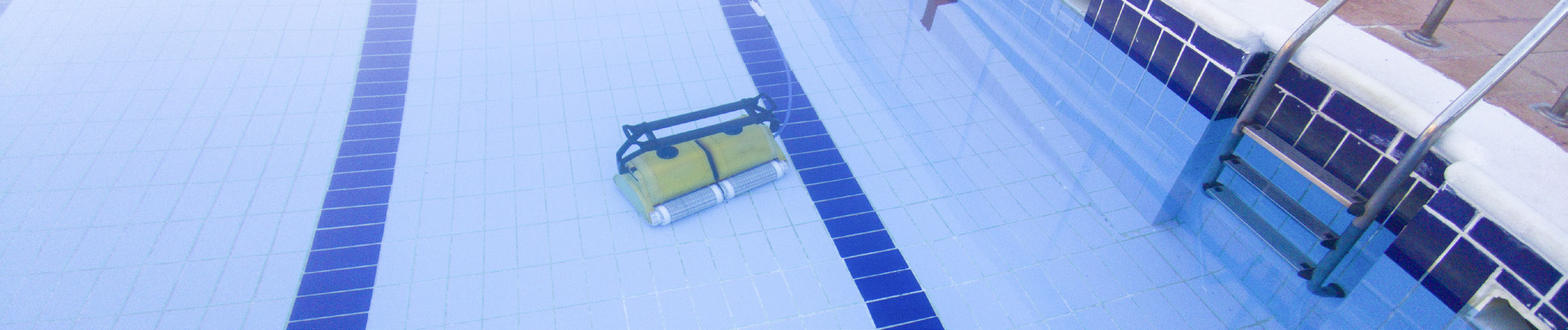 An overhead view of a rectangular swimming pool with blue tiles and a robotic pool cleaner at the bottom.